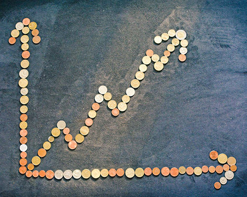 An upwards-trending graph made of coins on a textured blue background